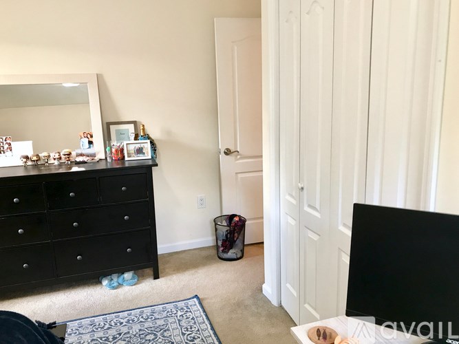 A black dresser with a mirror above it and a trash can to the side.