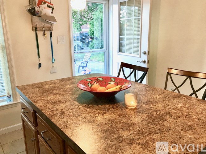 A bowl of fruit sits on a countertop in a kitchen.