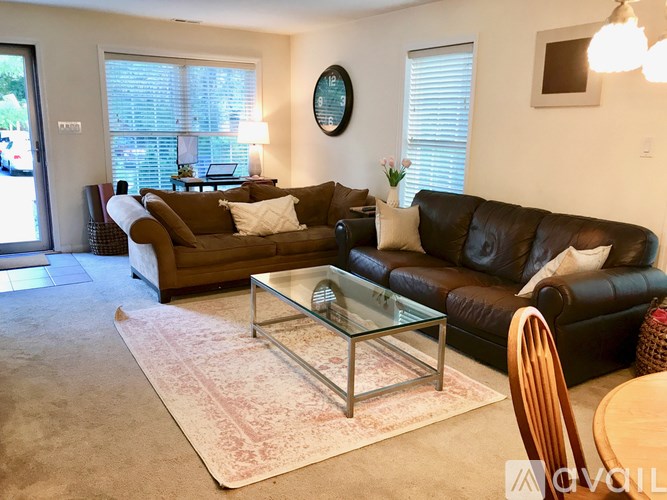 A living room with a glass coffee table and two couches.