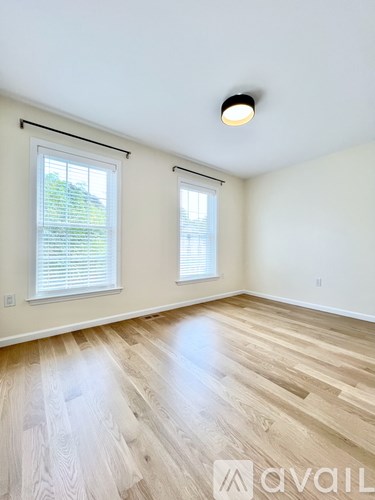 A living room with a wooden floor and a staircase in the background.