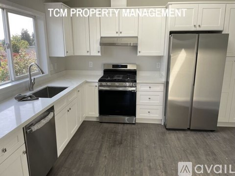 A kitchen with white cabinets and a stainless steel refrigerator is available for rent.