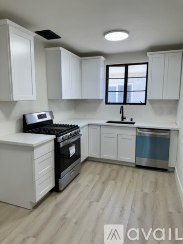 A kitchen with white cabinets and a black stove top oven.