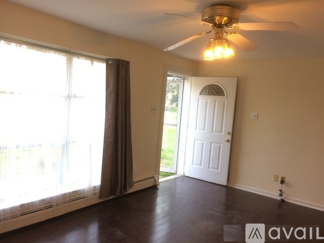 A room with a fan, sliding glass doors, and a white door.