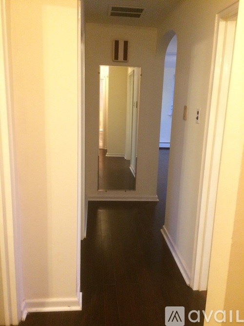 A hallway with a mirror and a door on the right.