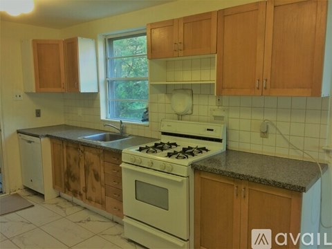 A kitchen with wooden cabinets and a white stove top oven.