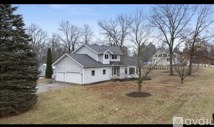 A house with a white exterior and a grey roof is surrounded by trees.