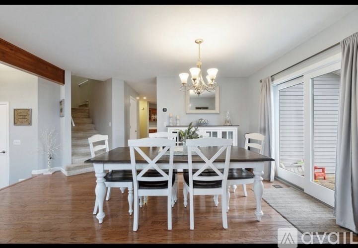 A dining room with a chandelier, a table with chairs, and a mirror on the wall.