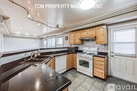 A kitchen with a black countertop and wooden cabinets is available for rent.