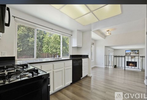 A modern kitchen with black stove top and white cabinets.