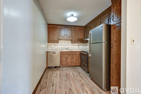 A kitchen with wooden cabinets and a refrigerator.