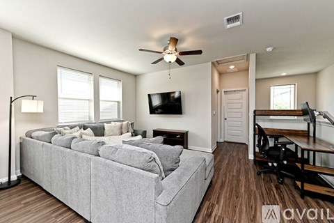 A living room with a grey couch and a ceiling fan.