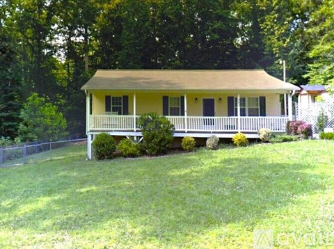A yellow house with a porch and a fence.
