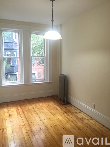 A room with wooden floors and a window overlooking a balcony.