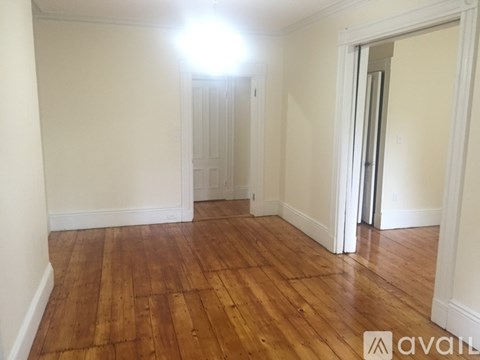 A room with wooden flooring and a doorway leading to another room.