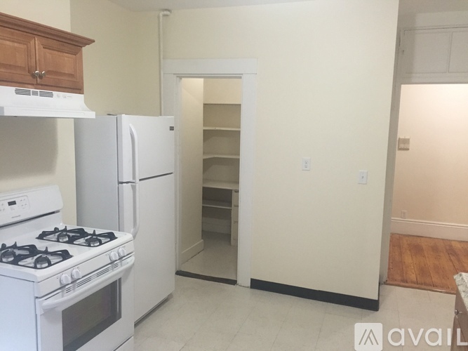 A kitchen with a white stove and refrigerator, and a doorway leading to another room.