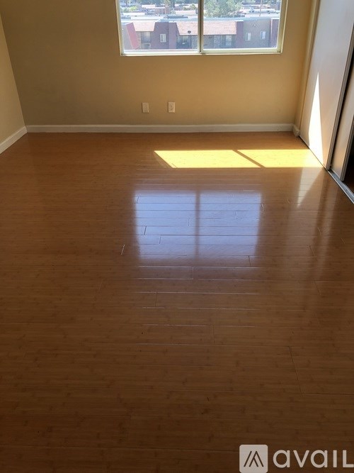 A room with wooden flooring and a window letting in sunlight.