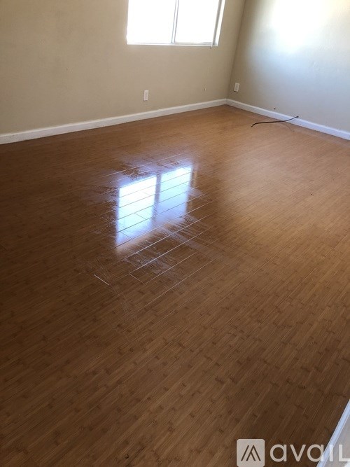 A room with wooden flooring and a window letting in sunlight.