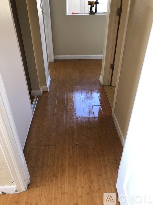 A hallway with wooden floors and white walls.
