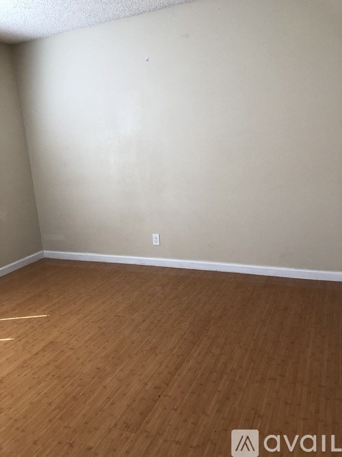 A room with wooden flooring and a wall socket.