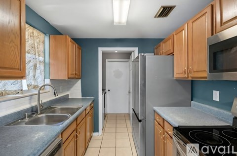 A kitchen with wooden cabinets and a stainless steel refrigerator.