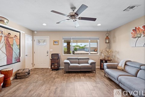 A living room with a grey couch and a ceiling fan.