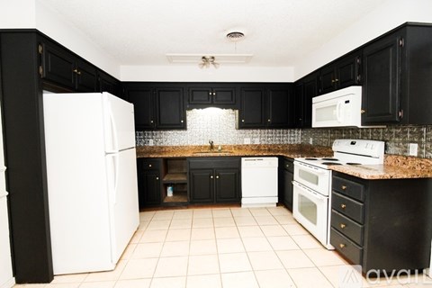 A kitchen with black cabinets and white appliances.