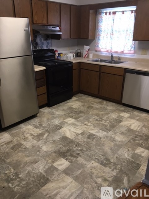 A kitchen with a marble floor and wooden cabinets.