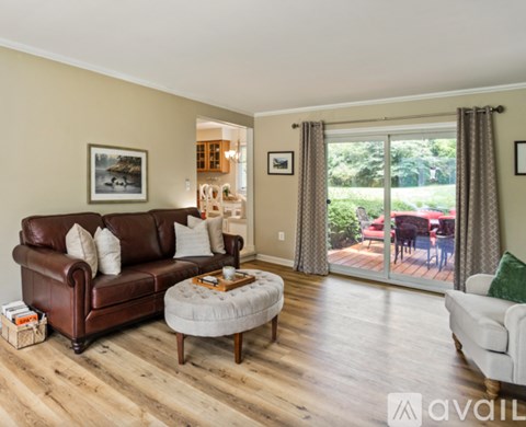 A living room with a brown leather couch and a white ottoman.