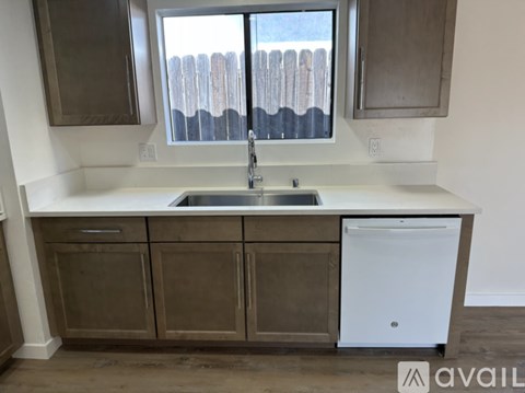 A kitchen with a white dishwasher and brown cabinets.
