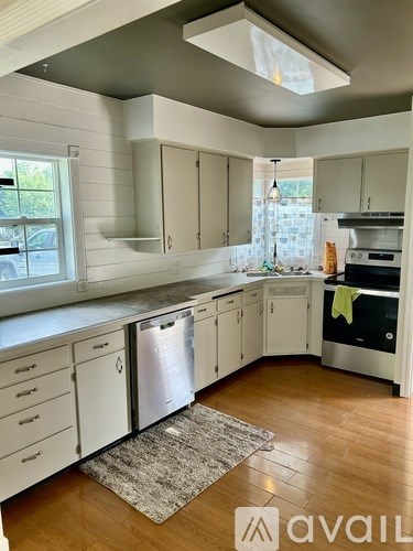 A kitchen with white cabinets and a wooden floor.
