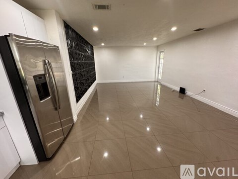 A spacious kitchen with a stainless steel refrigerator and a tiled floor.
