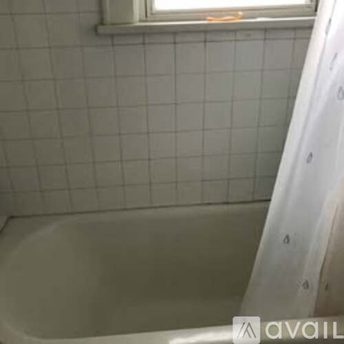 A white bath tub with a window above it.