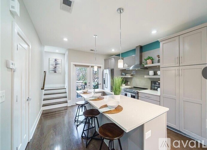 A kitchen with a white countertop and wooden floors.
