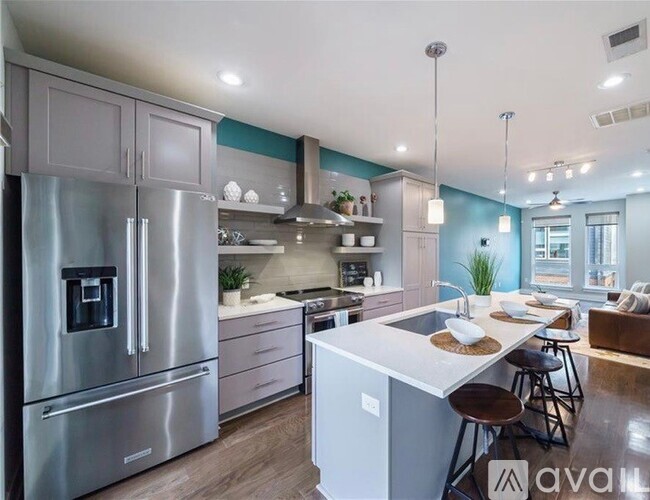 A modern kitchen with a stainless steel refrigerator and a white island.