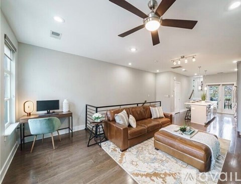 A living room with a brown leather couch and a ceiling fan.