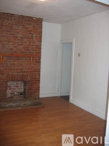 A room with a brick fireplace and wooden floors.