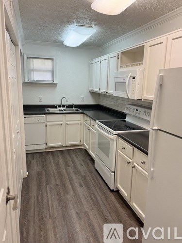 A kitchen with white appliances and wood floors.