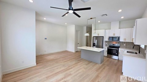 A spacious kitchen with a fan and wooden flooring.