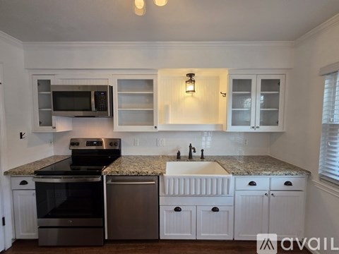 A kitchen with white cabinets and a granite countertop.
