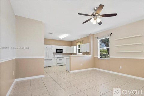 A kitchen with a fan on the ceiling and a dining area with a table and chairs.