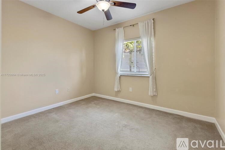 A room with a ceiling fan and a window with curtains.