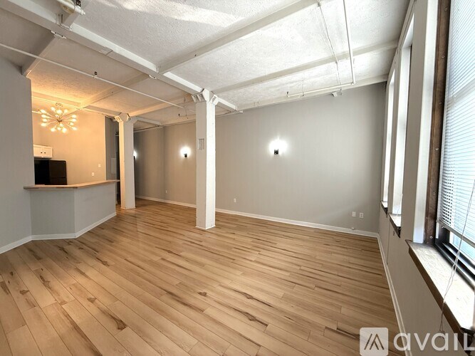 A spacious room with wooden flooring and white walls.