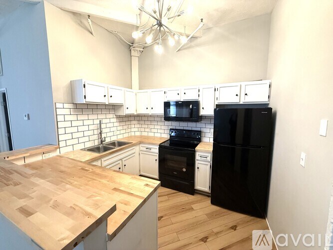 A kitchen with black appliances and wooden countertops.