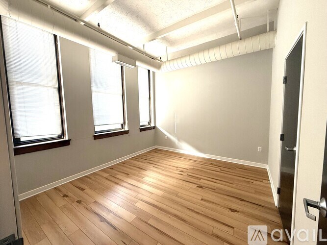 A room with wooden flooring and white walls, with a door on the right side.