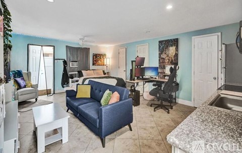 A living room with a blue couch and a white coffee table.