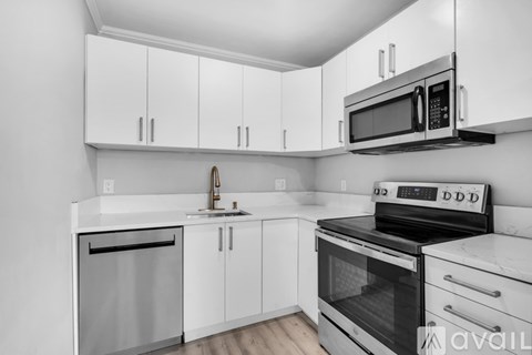A kitchen with white cabinets and black appliances.
