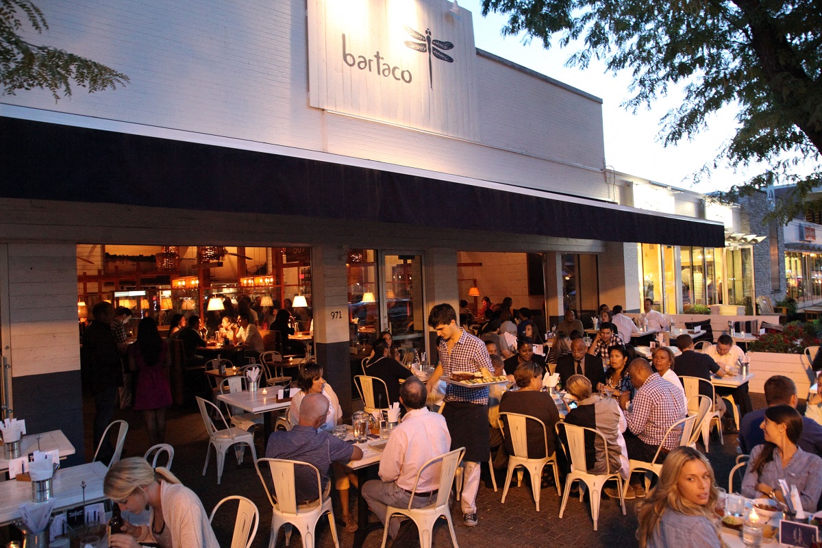people sitting at tables outside of a restaurant