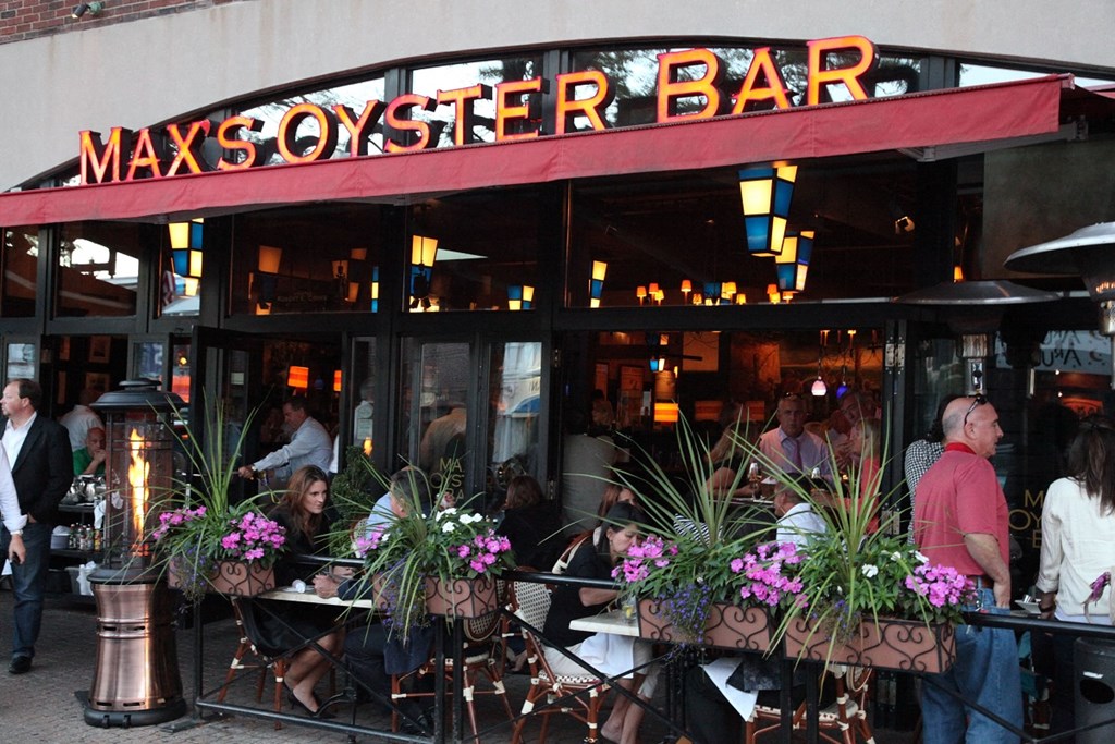 people are sitting at tables outside of a restaurant