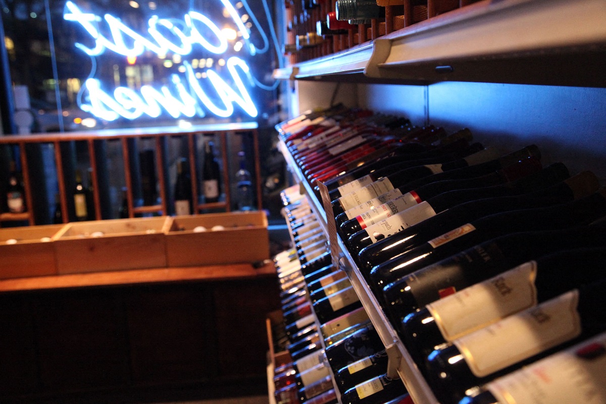 a display of wine bottles in a bar with a neon sign