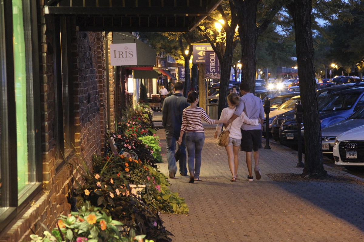 a group of people walking down a sidewalk at night